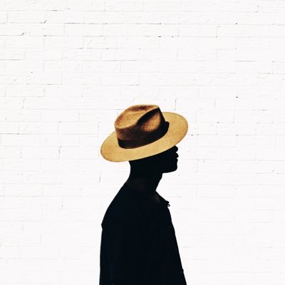 Dapper Lou with hat in front of white wall