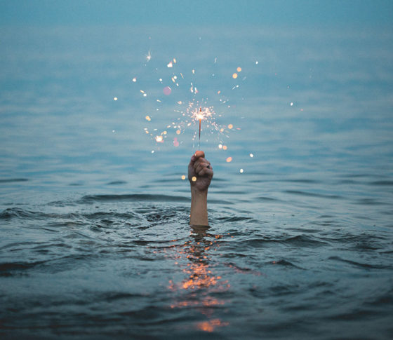 hand holding sparkler above water