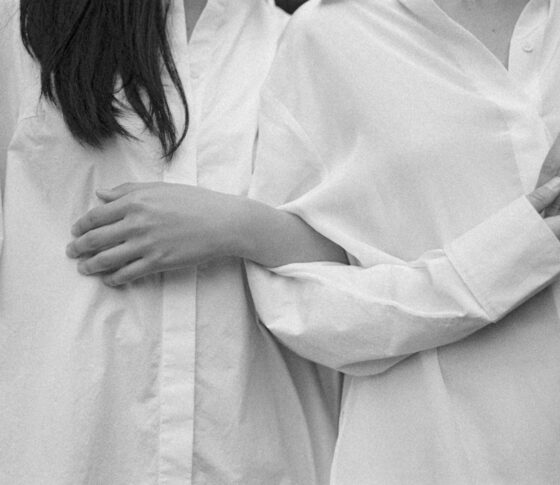 Two women in white shirts with interlocked arms